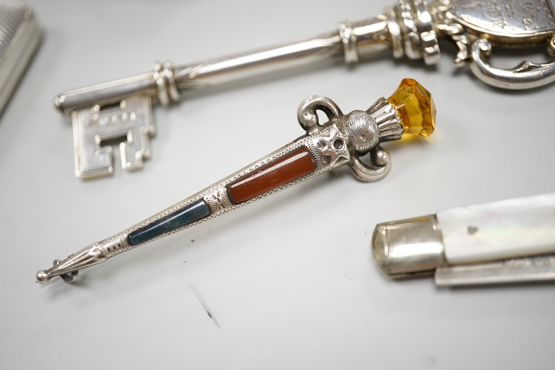 A George V silver presentation key, Vaughton & Sons, Birmingham, 1910, 10.2cm, together with a silver cigarette case, a silver and mother of pearl fruit knife, a miniature 925 demi-fluted teapot and a Scottish hardstone